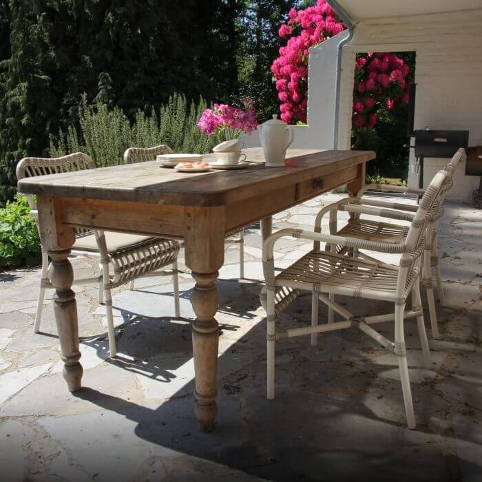 A charming outdoor dining area with a wooden table, chairs, and potted flowers, creating a cozy and inviting atmosphere.