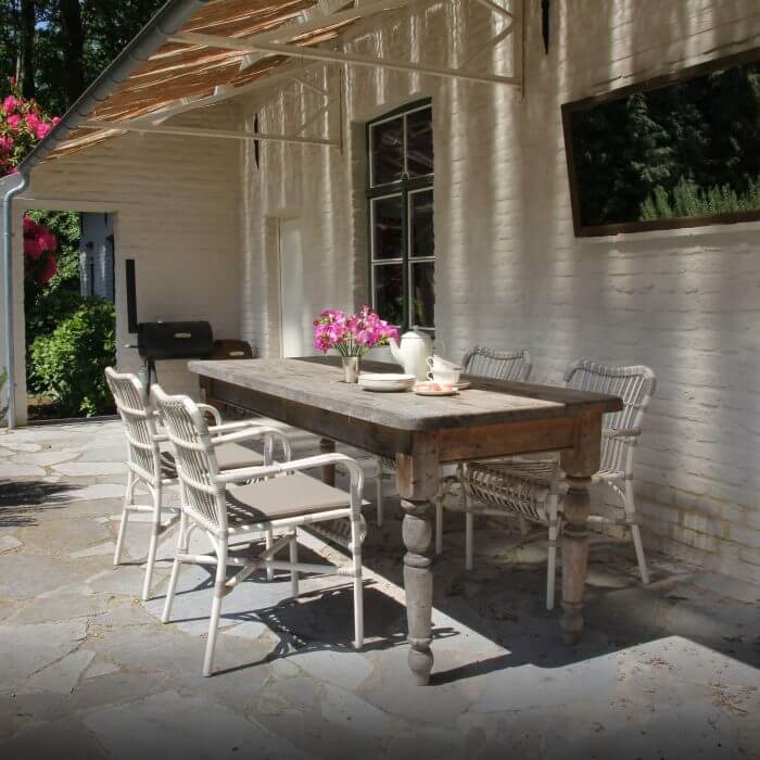 A charming al fresco dining setup with a wooden table, chairs, and carefully arranged tableware, providing a delightful outdoor dining experience