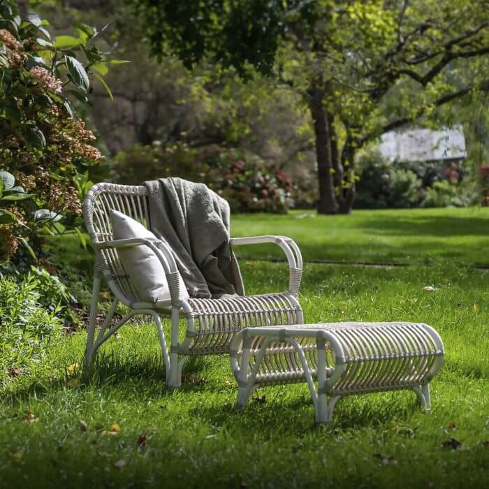A comfortable outdoor lounge chair with a matching footrest, providing a relaxing spot to unwind and enjoy the outdoors.