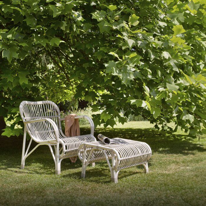 A stylish outdoor lounge chair accompanied by a convenient footrest, creating a cozy and serene spot for outdoor relaxation.